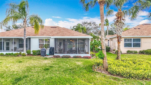 back of property with a lawn, a sunroom, and stucco siding