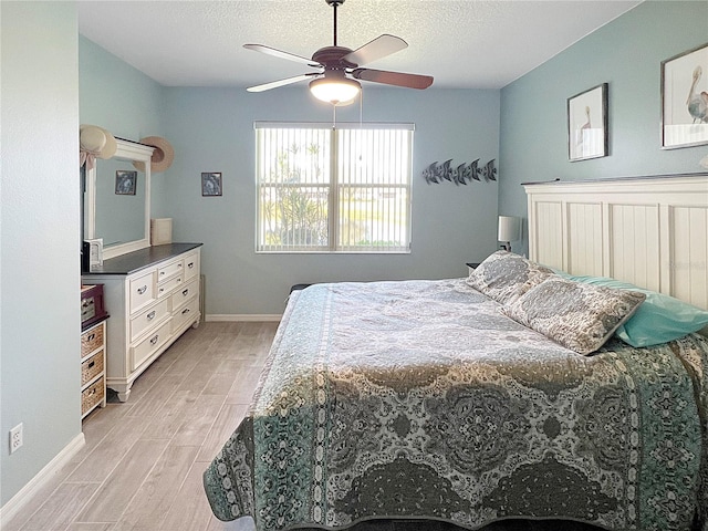 bedroom featuring baseboards, a textured ceiling, light wood-type flooring, and a ceiling fan