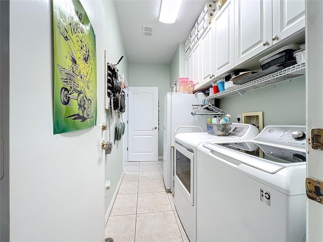 laundry area with light tile patterned floors, visible vents, baseboards, cabinet space, and separate washer and dryer