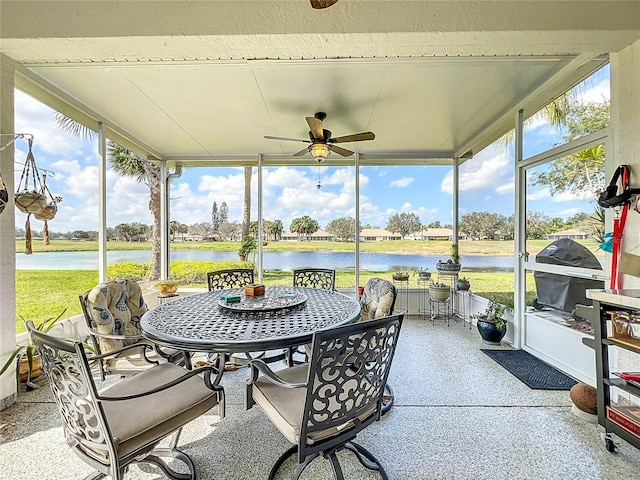 sunroom featuring a ceiling fan and a water view