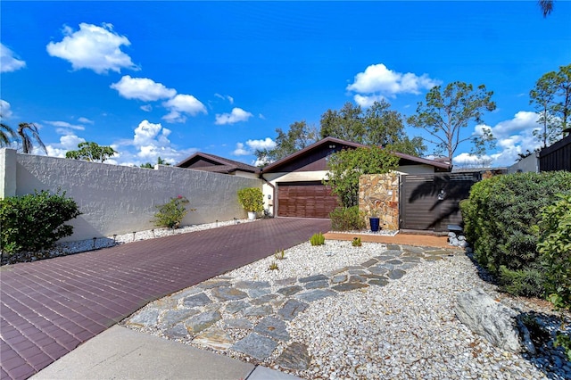 view of home's exterior with an attached garage, stone siding, fence, and decorative driveway