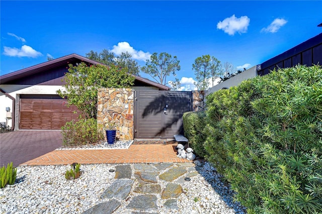 view of side of home with stone siding, driveway, and fence