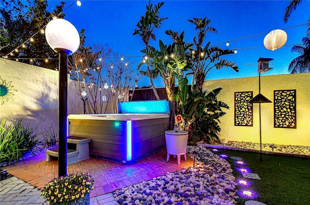 view of patio featuring fence and a hot tub