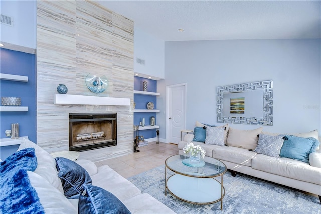 tiled living room featuring built in features, a fireplace, visible vents, a textured ceiling, and high vaulted ceiling