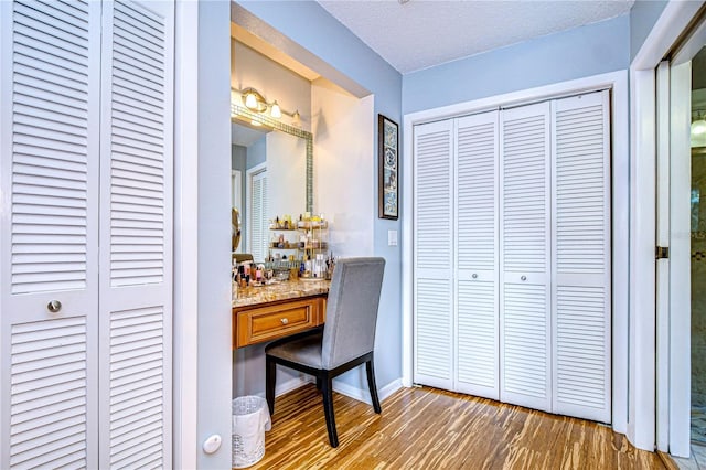 office area featuring a textured ceiling, baseboards, and wood finished floors