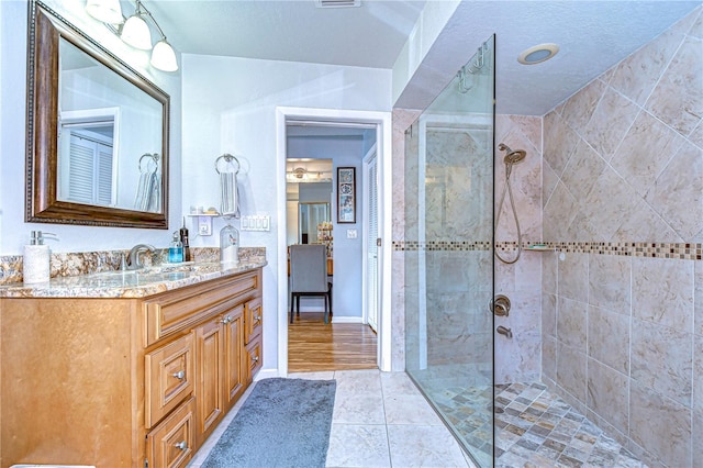 bathroom with tile patterned flooring, baseboards, a walk in shower, and vanity