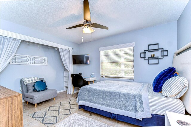 bedroom featuring a ceiling fan, a textured ceiling, and tile patterned floors