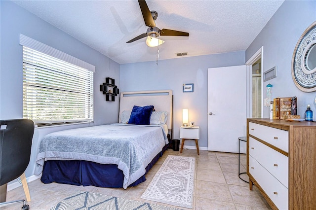 bedroom with light tile patterned floors, baseboards, visible vents, ceiling fan, and a textured ceiling