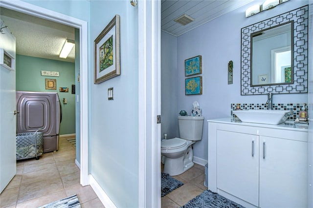 bathroom with washer / clothes dryer, visible vents, toilet, vanity, and tile patterned flooring