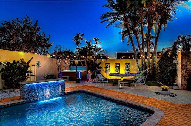 pool at twilight with fence private yard, a jacuzzi, and a patio