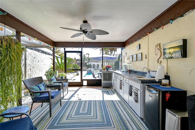 sunroom with ceiling fan and a sink