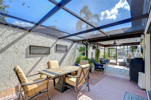 view of patio featuring ceiling fan, glass enclosure, and outdoor dining area