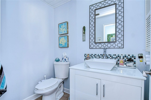 bathroom featuring baseboards, vanity, toilet, and decorative backsplash