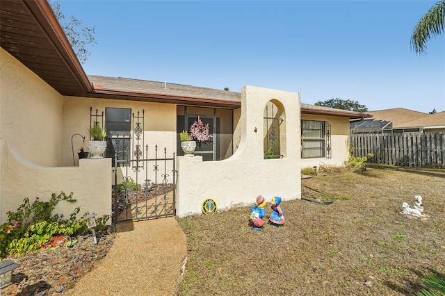 view of front of property with a gate, fence, and stucco siding