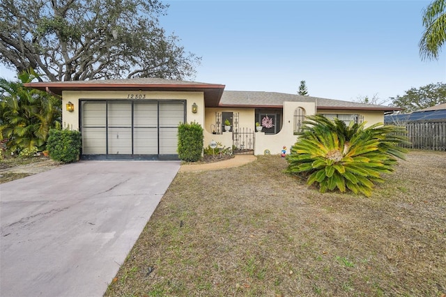 ranch-style home with driveway, an attached garage, fence, and stucco siding