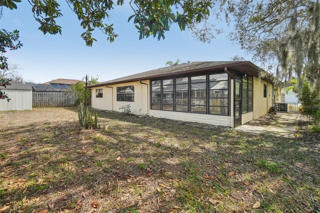 rear view of property featuring central AC, fence, and a sunroom