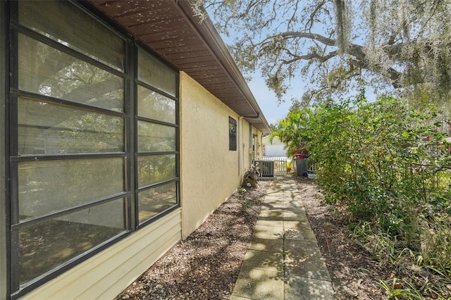 view of side of property with fence, central AC unit, and stucco siding