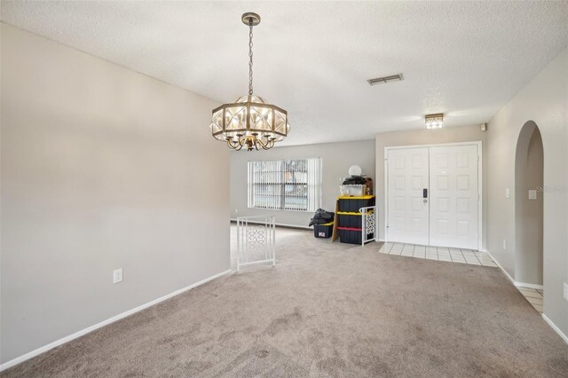 interior space featuring arched walkways, a notable chandelier, visible vents, a textured ceiling, and baseboards