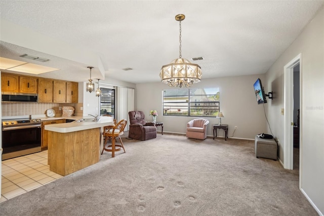 kitchen with a notable chandelier, appliances with stainless steel finishes, a sink, and light colored carpet