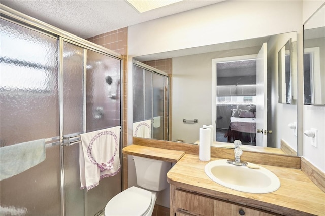 bathroom featuring a textured ceiling, toilet, vanity, a stall shower, and ensuite bath