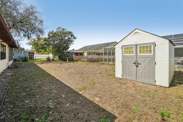 view of yard featuring a shed, an outdoor structure, and fence