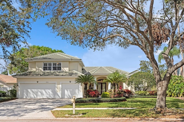 view of front of house featuring concrete driveway, a tiled roof, an attached garage, a front yard, and stucco siding