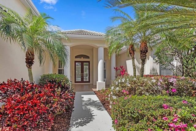 entrance to property featuring french doors, a tiled roof, and stucco siding