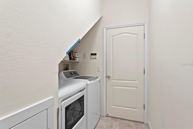 washroom with laundry area, a textured wall, washer and clothes dryer, and light tile patterned floors