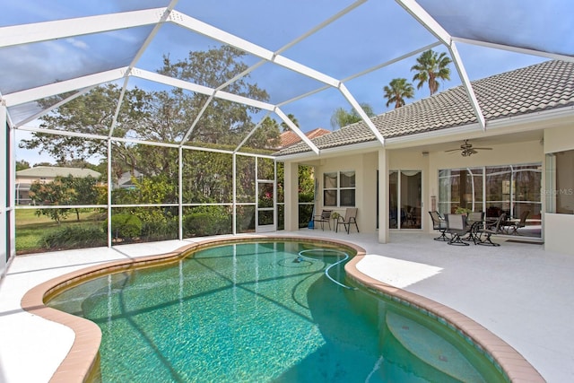 pool with a patio area, glass enclosure, and a ceiling fan