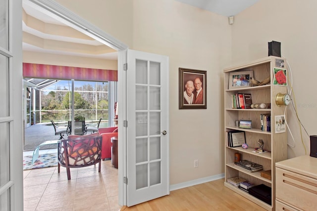 doorway to outside featuring a sunroom, light wood-style flooring, and baseboards