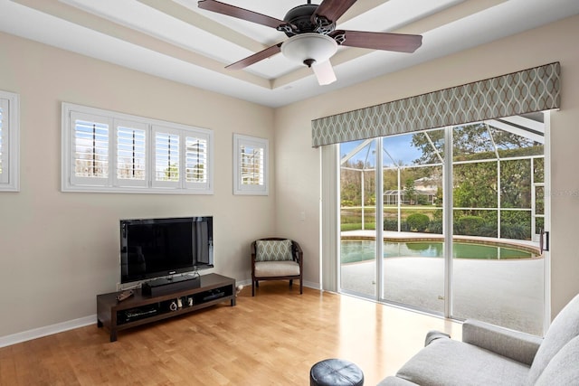 sitting room with a ceiling fan, baseboards, and light wood finished floors