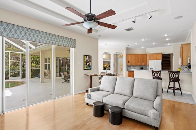 living area featuring baseboards, visible vents, arched walkways, ceiling fan, and light wood-type flooring