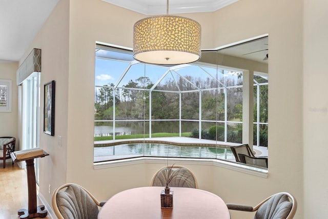 dining space featuring a water view, a sunroom, crown molding, and a wealth of natural light