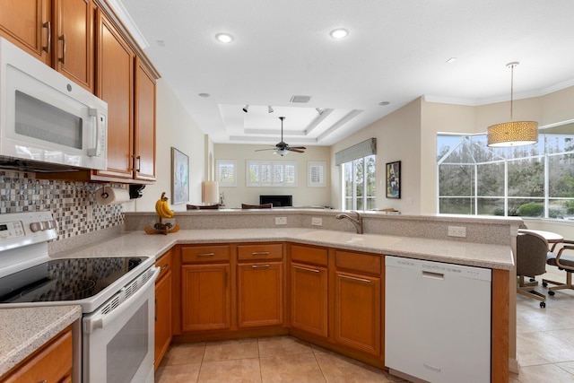 kitchen with white appliances, brown cabinets, a sink, and a raised ceiling