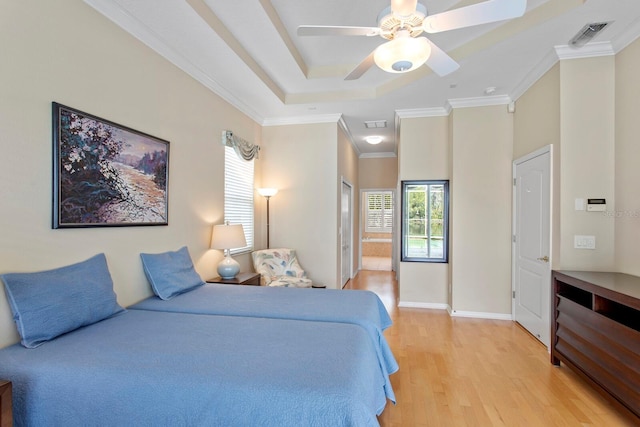 bedroom featuring connected bathroom, baseboards, light wood-style floors, ornamental molding, and a tray ceiling