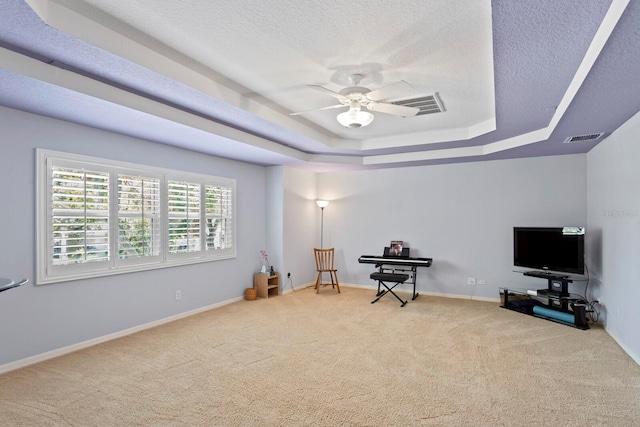 interior space featuring carpet floors, a raised ceiling, visible vents, and a ceiling fan