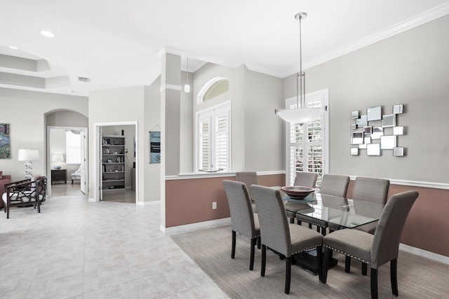 dining room with ornamental molding, arched walkways, baseboards, and light tile patterned floors