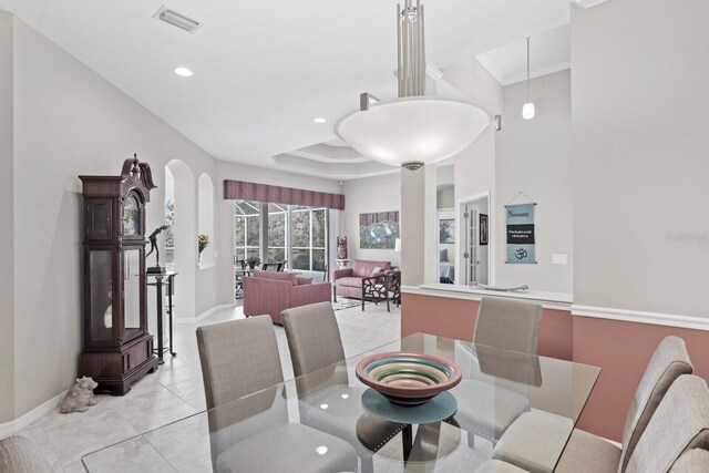 dining space with a tray ceiling, visible vents, baseboards, and light tile patterned floors