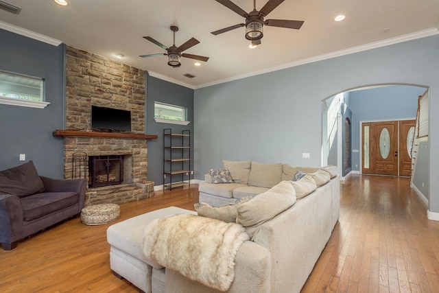 living area featuring arched walkways, wood-type flooring, visible vents, and crown molding