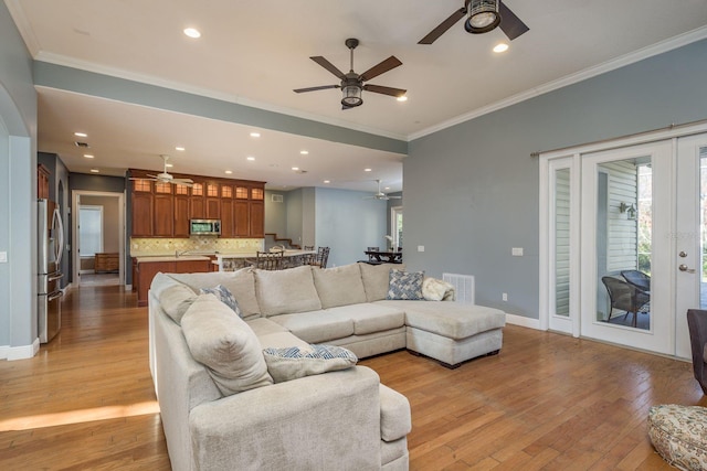 living area with french doors, visible vents, crown molding, and light wood-style flooring