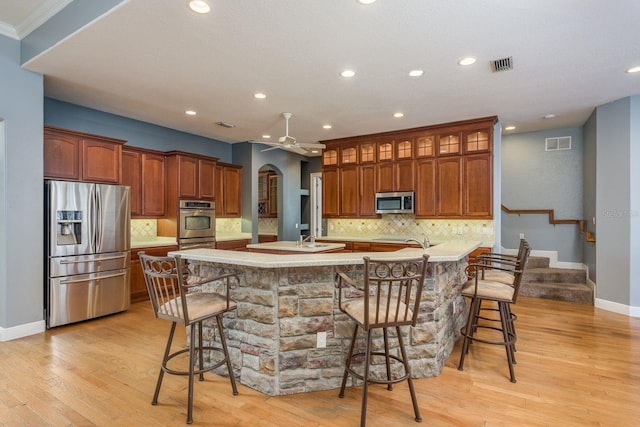 kitchen with stainless steel appliances, arched walkways, visible vents, and a breakfast bar area