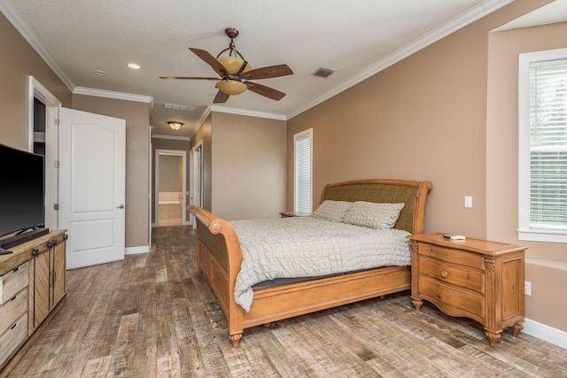 bedroom with baseboards, crown molding, visible vents, and wood finished floors