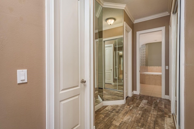 hall featuring a textured wall, ornamental molding, and dark wood finished floors