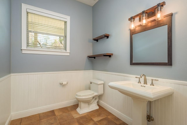 half bath featuring a wainscoted wall and toilet