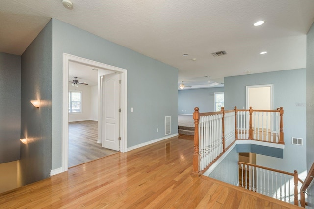 corridor with visible vents, an upstairs landing, and wood finished floors