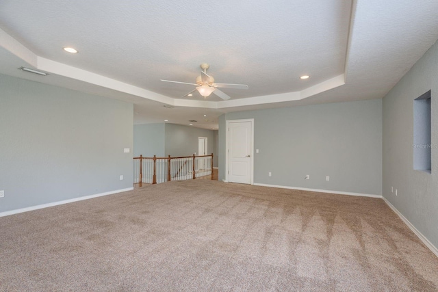 empty room featuring carpet, a raised ceiling, and baseboards