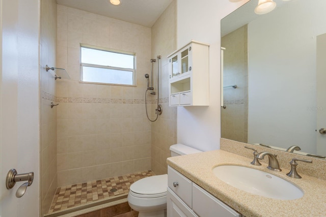 full bathroom featuring tiled shower, vanity, and toilet