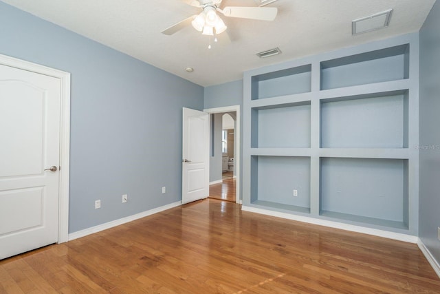 unfurnished bedroom with wood finished floors, visible vents, and baseboards