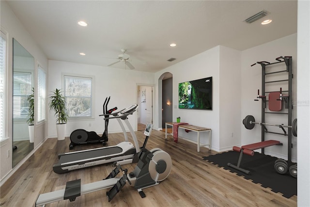 workout room featuring visible vents, arched walkways, wood finished floors, and recessed lighting