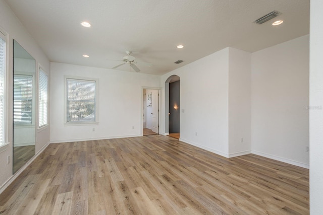 empty room with arched walkways, ceiling fan, light wood-style flooring, recessed lighting, and visible vents